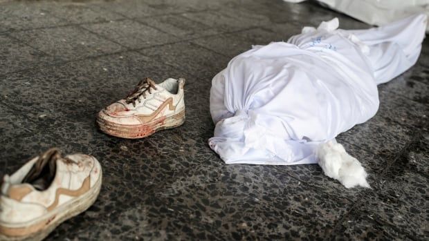 Shoes stained with blood placed next to a white body bag.