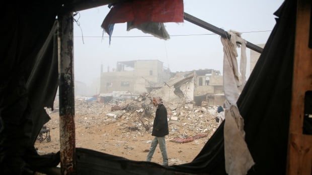 A person walks amid the rubble of destroyed buildings.