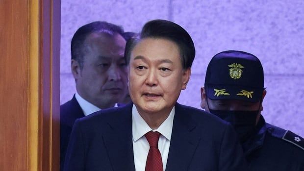 South Korea’s impeached President Yoon Suk Yeol walks through a door. 