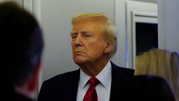 U.S. President Donald Trump looks toward a group of reporters.