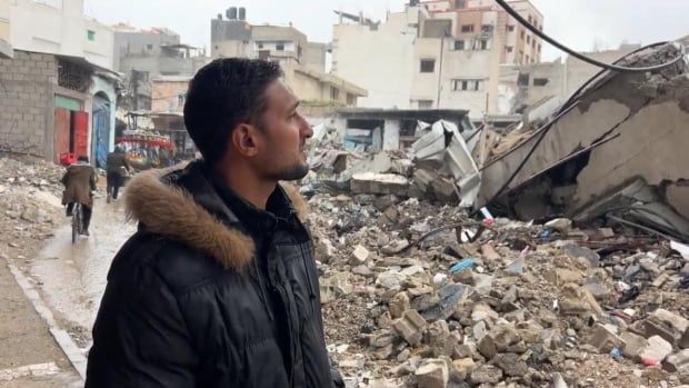 A man looks at rubble.