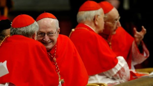 Four cardinals, dressed in traditional red vestments, talk among themselves.