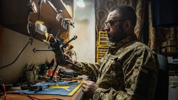 A Ukrainian soldier sits at a desk in a drone-repair workshop, near Siversk, Ukraine.