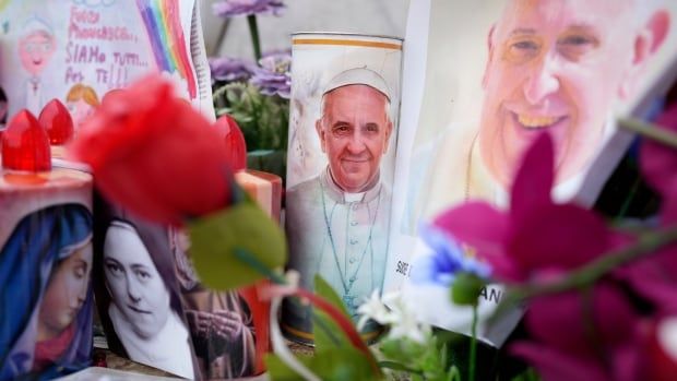 Pictures of the pope sit amid candles and flowers