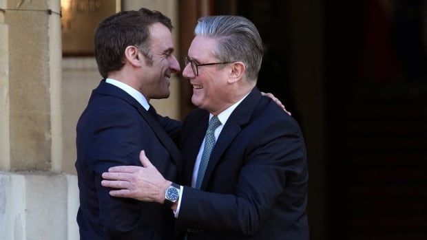 Two smiling men greet each other with a hug.