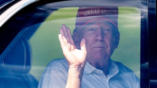 A person waves from the backseat of a car.