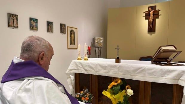 A person in religious garb sits in a wheelchair in front of an altar.