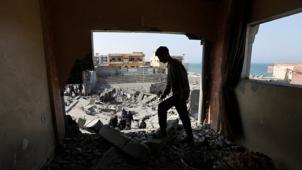 Palestinians inspect the site of an Israeli strike on a residential building, in Deir Al-Balah in the central Gaza Strip