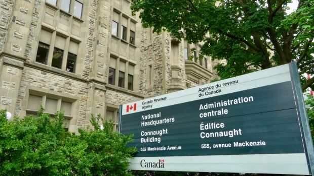 A photo of the front entrance sign of the National Headquarters for the Canada Revenue Agency at 555 Mackenzie Avenue in Ottawa, written in both French and English.