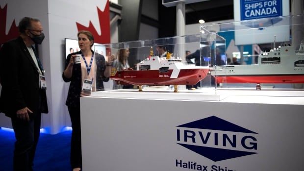 A model of a red and white ship sits in a plexiglass display case on a pedestal that says "Irving Shipbuilding."