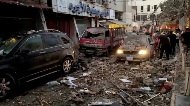 Damaged cars  are seen in  rubble on a street