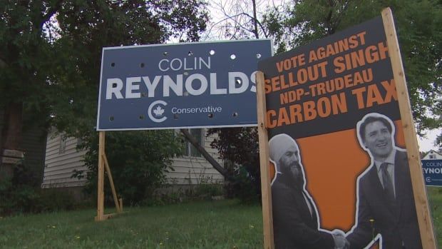 A sign reading "Colin Reynolds Conservative" on a lawn, next to another sign with images of Jagmeet Singh and Justin Trudeau and the words "vote against sellout Singh."