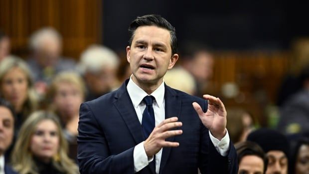 A man in a dark suit gestures with his hands as he speaks in the House of Commons.