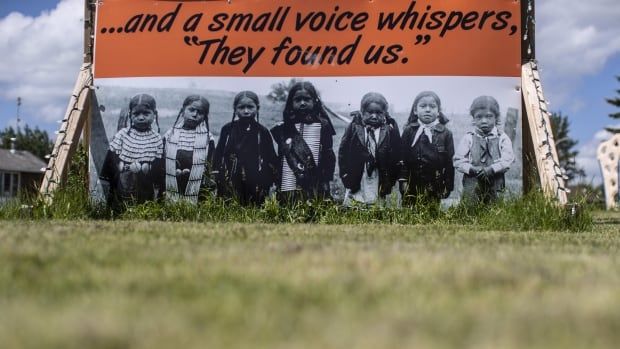 An orange sign reads "...and a small voice whispers, they found us" above the images of several children. 