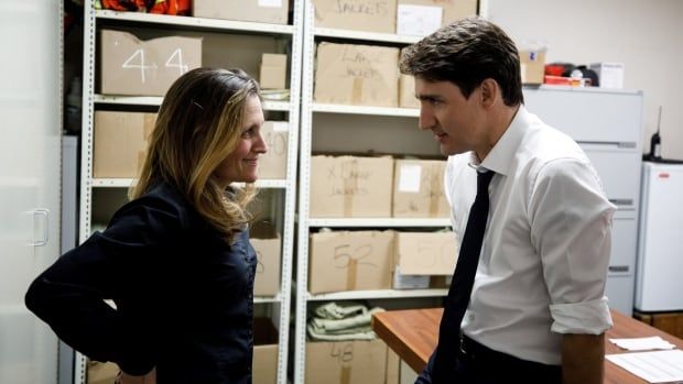 A woman and man look at each other with boxes in the background.