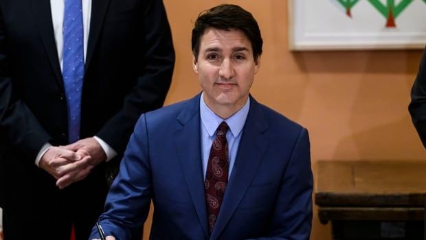 Prime Minister Justin Trudeau signs a piece of paper.