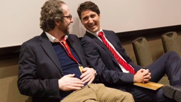 Two men sit on a couch, laughing