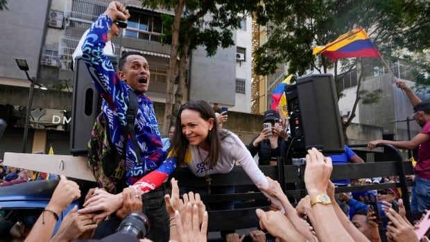 A woman greets a crowd from the cab of a truck.