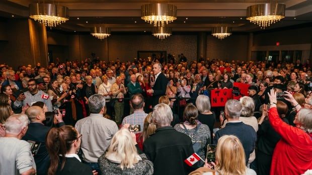 A man speaks to a room of people.