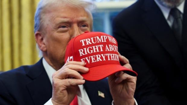 U.S. President Donald Trump holds a red cap that says, "Trump was right about everything"