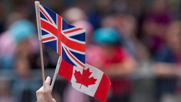 A spectator holds up the Canadian and Union Jack flags during a visit by late Queen Elizabeth to Ottawa.