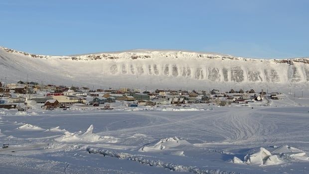 A photo of a community in the distance, surrounded by snow.