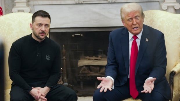 Two men sit in chairs in front of a fire place.