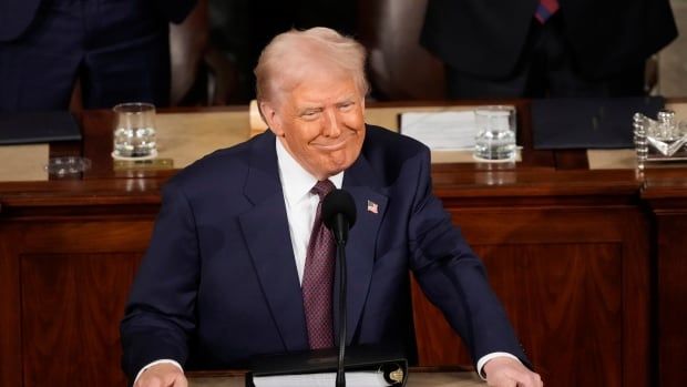 A man in a suit smiles ata podium