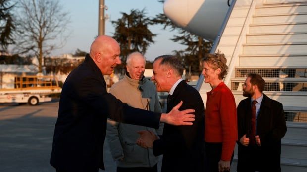 two men shake hands outside of a plane