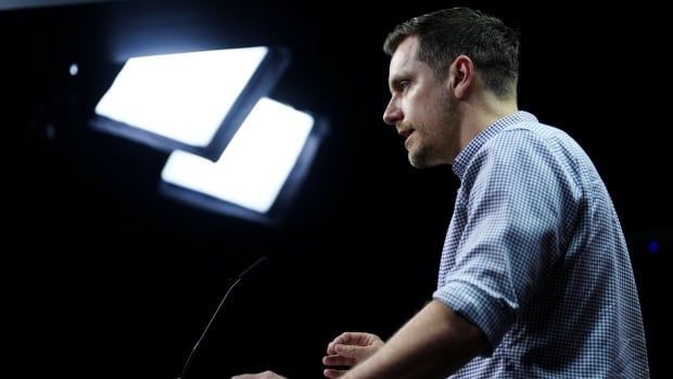 A union leader under television lights at a news conference.