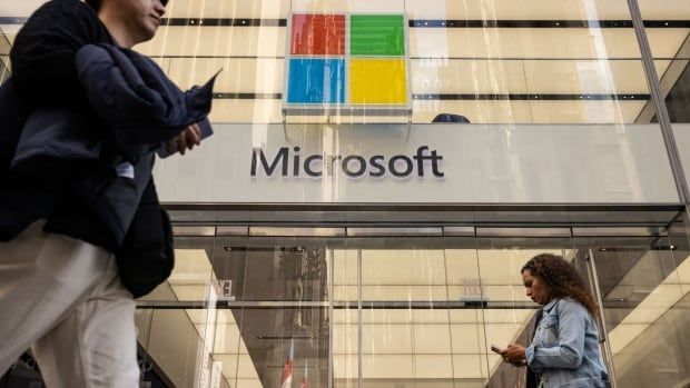 Pedestrians walk past a Microsoft sign outside a store in New York.