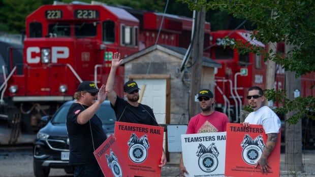 Members of the Teamsters Canada Rail Conference hold signs during a picket at the CPKC Kinnear Yard at 270 Gage Ave. South in Hamilton, Ont., Thursday, Aug. 22, 2024. CN and CPKC workers across the country have been locked out causing a shutdown that cuts off a nationwide transport lifeline. 