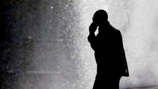 A silhouetted man talks on his cellphone.