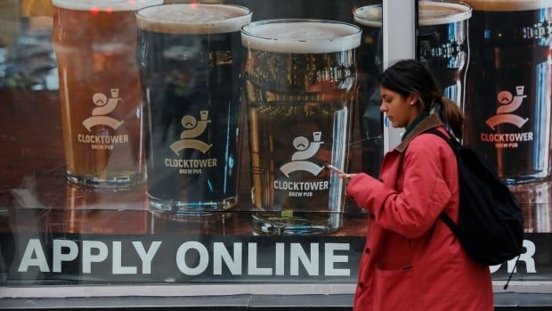 A woman walks by a window with a sign that says "apply online."