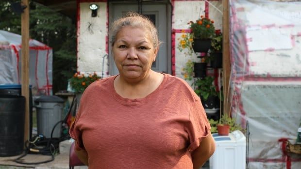 A woman in a salmon-coloured t-shirt is pictured in front of a trailer in Conklin, Alta.