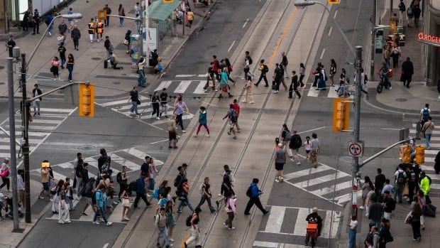 An aerial shot showing many people crossing the road in all directions in a city. 