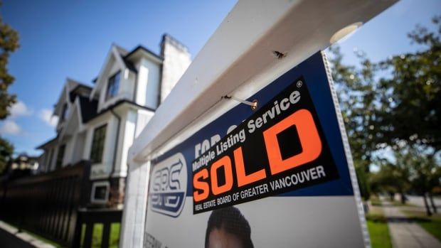 A realtor's sign that reads 'SOLD, REAL ESTATE BOARD OF GREATER VANCOUVER'.