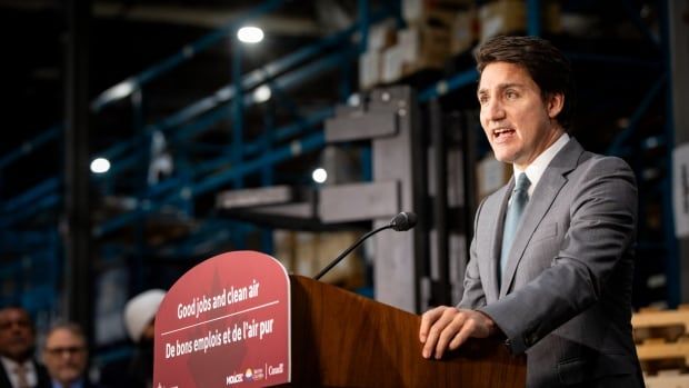 Prime Minister Justin Trudeau speaks from a red podium at night that has the words, Good jobs and clean air, on it in English And French.