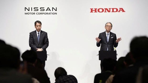 Two men speak to an audience, standing in front of a screen that bears the Nissan and Honda logos.