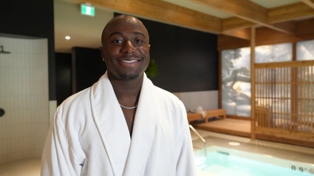 A man wearing a white robe poses for a photo in front of a pool.