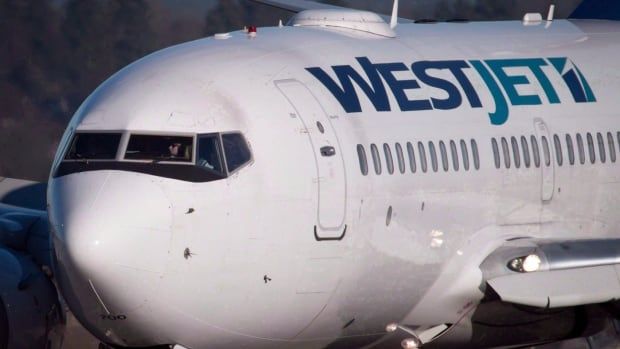 A white plane with 'WestJet' written on the side in blue.