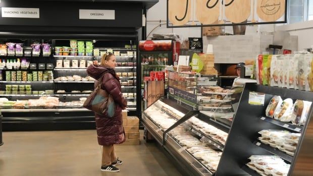 A woman standing in a grocery store aisle.