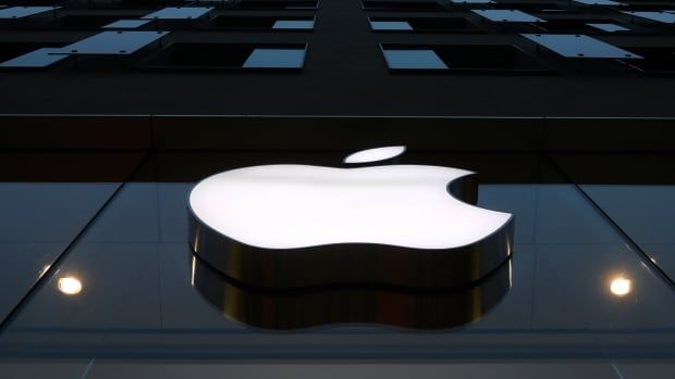 A large Apple logo, seen from a low angle, is displayed on the side of a building.