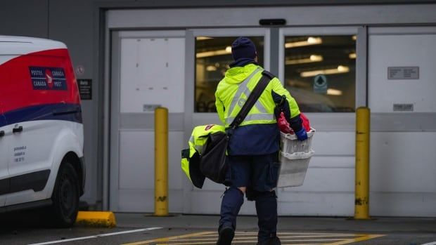 A mail carrier holds a bin of mail