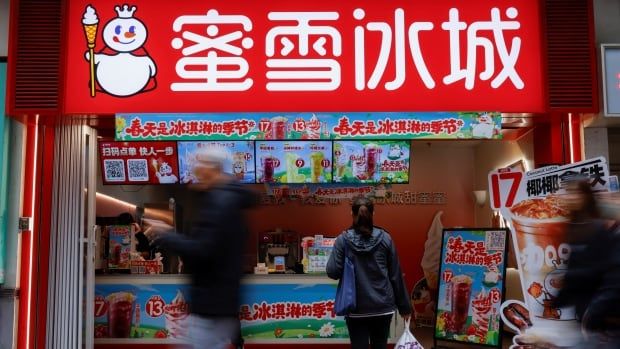 People walk past a bubble tea storefront with a red sign featuring a snow king mascot and white Chinese characters that read "Mixue Bingcheng." 