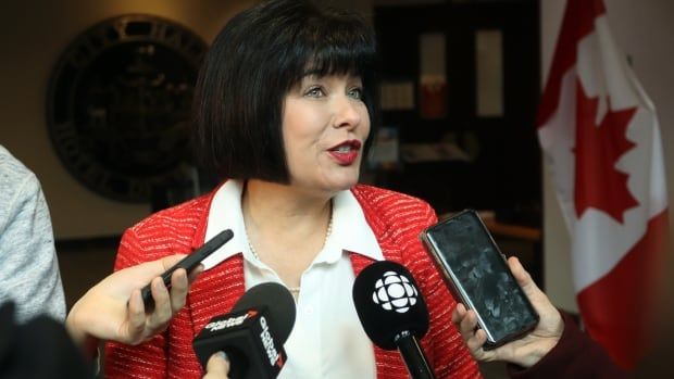 A woman speaking with various microphones in front of her. 