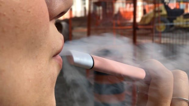 Woman releases vapour after use a pink e-cigarette