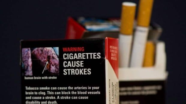 Two packages of cigarettes are shown. One, in the foreground, displays a health warning, saying cigarettes cause strokes.