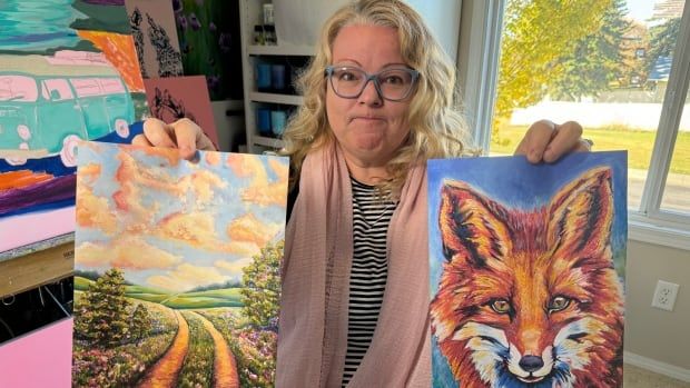 Woman holds up paintings of a country road and a fox