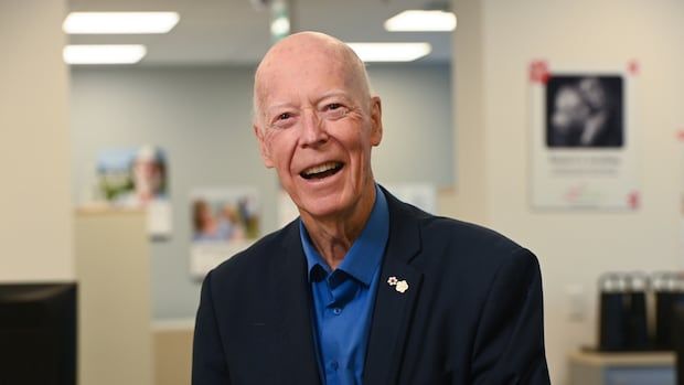 Man in a blazer and blue shirt smiles